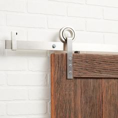 a close up of a wooden door handle on a white brick wall with metal hardware