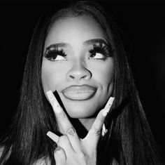 a black and white photo of a woman holding her hands up to her face with makeup on