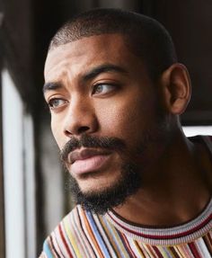 a close up of a man with a beard and striped shirt looking off to the side