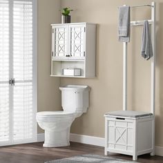 a white toilet sitting next to a cabinet in a bathroom