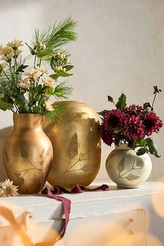 three vases filled with flowers sitting on top of a white table next to each other