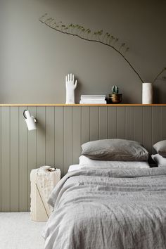 a bed sitting next to a wooden shelf on top of a wall