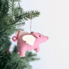 a pink pig ornament hanging from a christmas tree