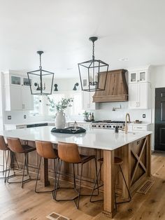 a large kitchen with an island and bar stools in the center, surrounded by wooden flooring