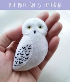 a hand holding a small white owl with yellow eyes