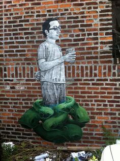 a mural on the side of a brick building depicts a man holding a coffee cup