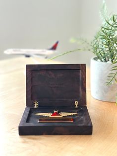 a wooden box with a pen in it sitting on a table next to a potted plant