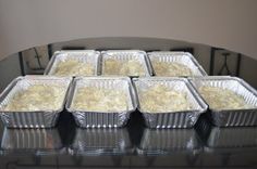 six aluminum pans filled with food sitting on top of a black counter next to each other