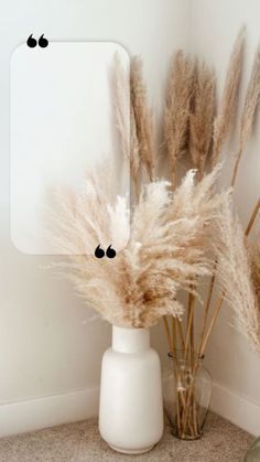 some dry grass in a white vase next to a mirror with black dots on it