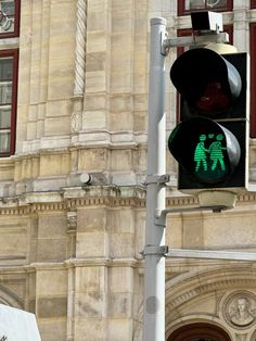 a green traffic light sitting in front of a tall building with two people on it