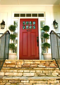 a red front door with two potted plants on the steps