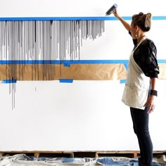 a woman standing in front of a wall with a large piece of art hanging on it