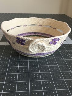 a white basket with purple flowers on it sitting on a counter top next to a knife