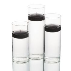 three clear glass vases with black candles in them