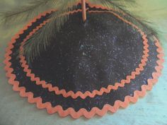 an ornament hanging from a pine tree on top of a table with orange trim