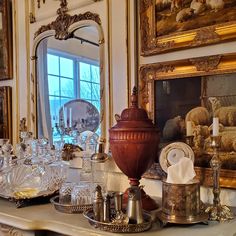 a table topped with lots of glassware next to a mirror