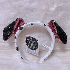 a white and black headband with two ears on it's side, next to a tag