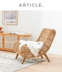 a wicker chair sitting on top of a wooden floor next to a white rug