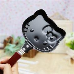 a person holding a black and silver hello kitty spatula