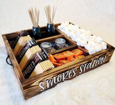 a wooden tray filled with marshmallows and other snacks