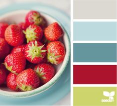 a bowl full of strawberries sitting on top of a blue and green tablecloth