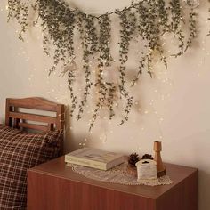 a room with a bed and some plants hanging on the wall next to a night stand