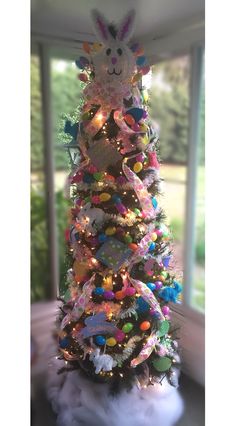 a decorated christmas tree in front of a window with lots of lights and decorations on it