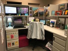 an office cubicle with desk, computer and pictures on the wall