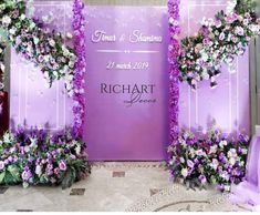 purple and white flowers decorate the backdrop for a wedding ceremony