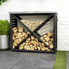 a firewood rack with logs in it on the ground next to a potted plant