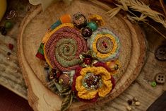 an arrangement of fabric flowers sitting on top of a piece of wood next to other items