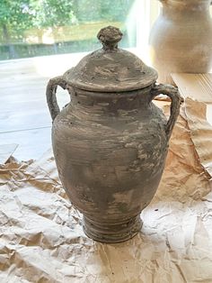 two vases sitting next to each other on top of a piece of paper covered ground