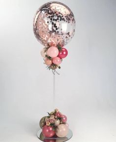 a balloon and some balloons on a stand with confetti in the bottom half