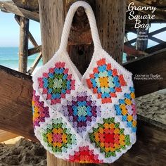 a colorful crocheted bag hanging from a wooden post next to the ocean with text overlay that says granny square bag