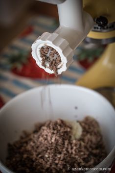 a blender is pouring chocolate into a white bowl with brown stuff in the bottom