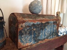 an old trunk sitting on top of a wooden table next to a ball of yarn