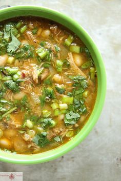 a green bowl filled with soup on top of a table