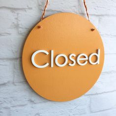 a close up of a sign on a brick wall with the word closed written in white