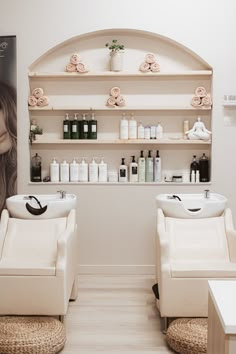 two white chairs sitting next to each other in front of a shelf filled with bottles