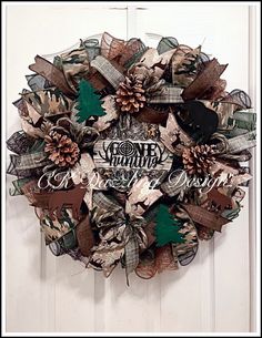 a wreath hanging on the front door with pine cones and ribbon around it that says merry christmas