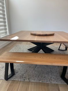 a wooden table with two benches in front of it on carpeted floor next to white wall