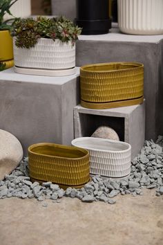 some white and yellow planters sitting on top of cement blocks next to graveled rocks