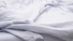 an unmade bed with white sheets and pillows