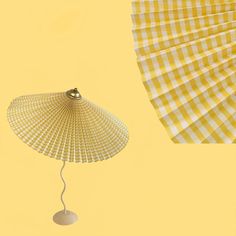 a yellow and white checkered umbrella next to a lamp on a light yellow background