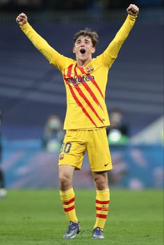 a soccer player with his arms in the air and his mouth wide open while standing on a field