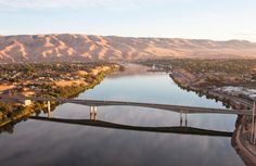 an aerial view of a bridge over a body of water with mountains in the background