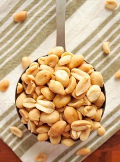 a spoon full of peanuts sitting on top of a table