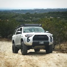 a white toyota truck driving down a dirt road