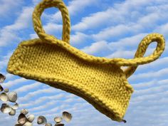 a yellow knitted bag with strings hanging from it's sides in the air