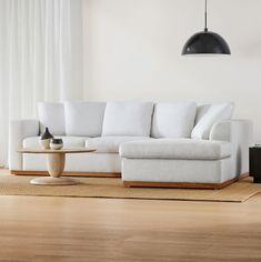 a white couch sitting on top of a hard wood floor next to a table and lamp